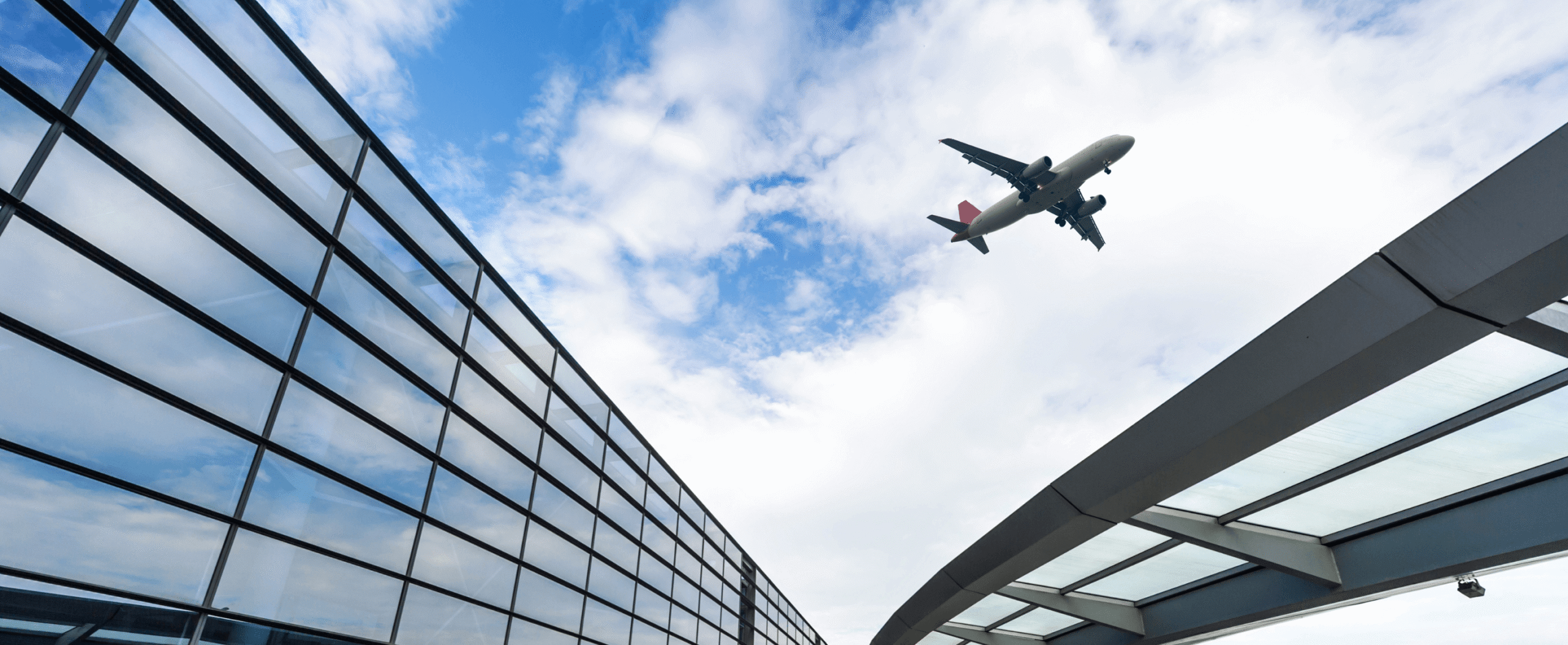 An airport departures area with an aeroplane visible overhead.